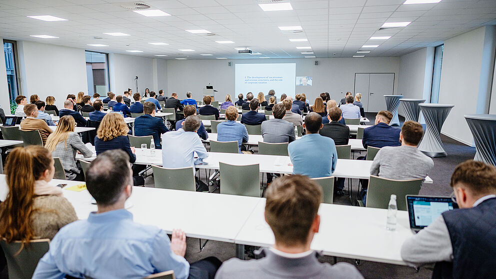 Viele Personen sitzen in einem Raum.